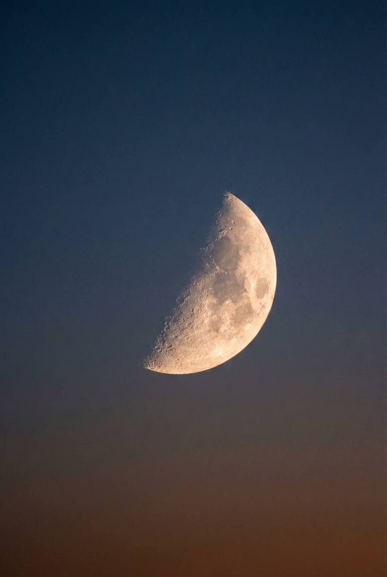 Glowing crescent moon against a dark, minimalist twilight sky.