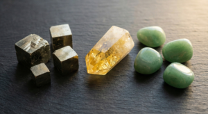 A high-quality flat-lay arrangement of powerful Money Crystals including raw Pyrite cubes, yellow Citrine points, and Green Aventurine stones on a dark slate background.