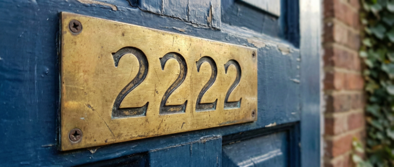 A realistic metal door number plate displaying 2222, symbolizing the stability and home-centered energy of Angel Number 2222.