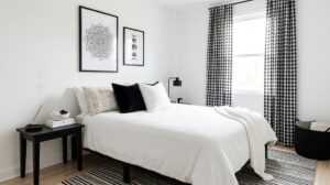 A serene bedroom showcasing black and white spiritual decor, featuring framed mandala and moon phase art, crisp white bedding, and black-and-white checkered curtains.